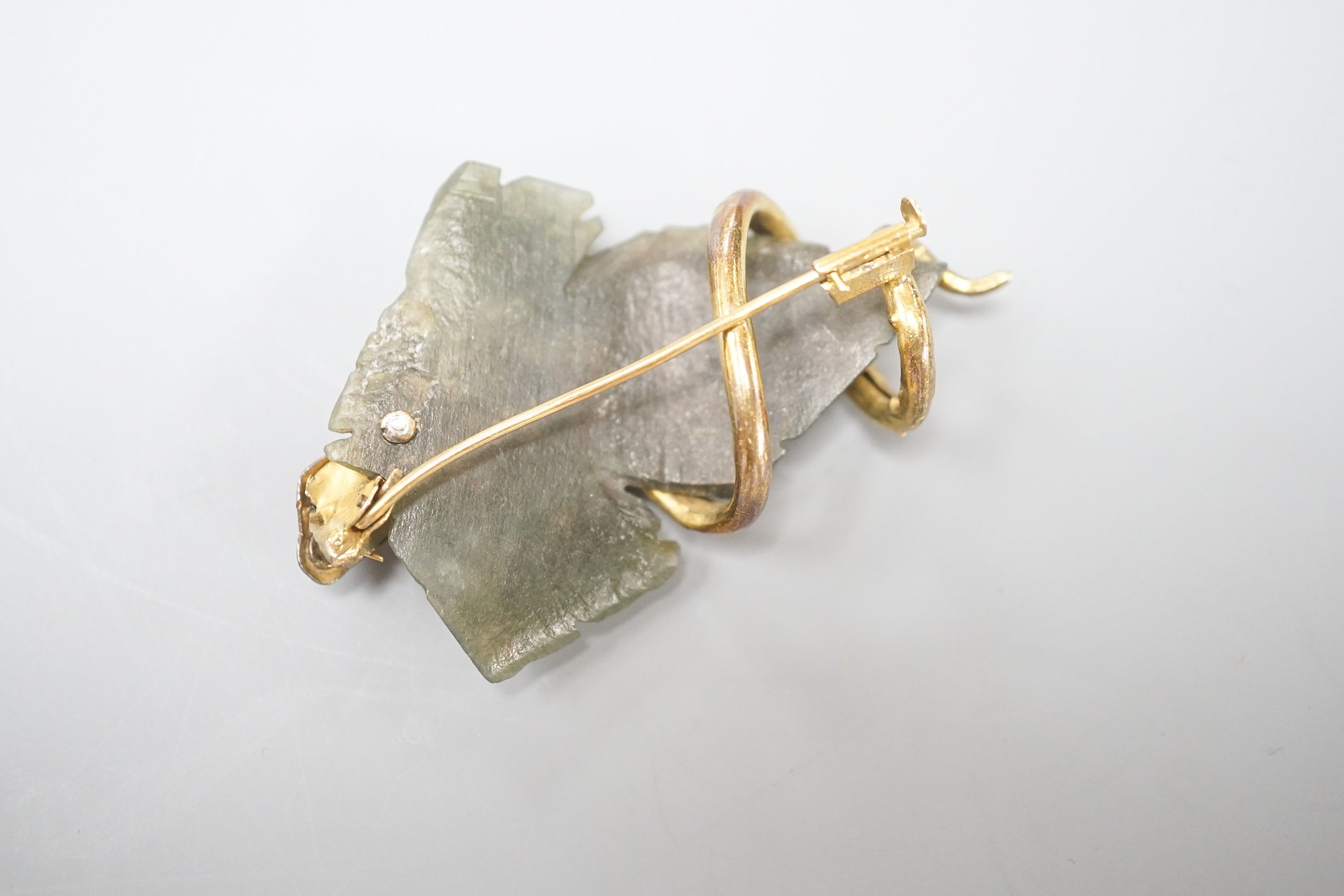 A continental yellow metal, garnet and nephrite set brooch, modelled as a leaf entwined with serpent, 56mm, gross weight 14 grams.